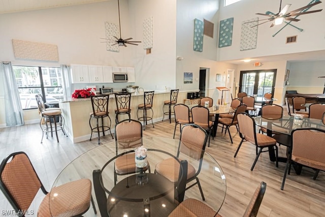 interior space with plenty of natural light, high vaulted ceiling, ceiling fan, and light wood-type flooring