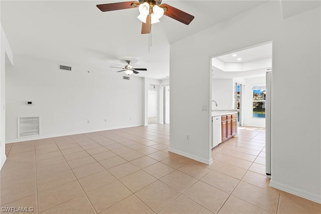 empty room with light tile floors, a raised ceiling, and ceiling fan