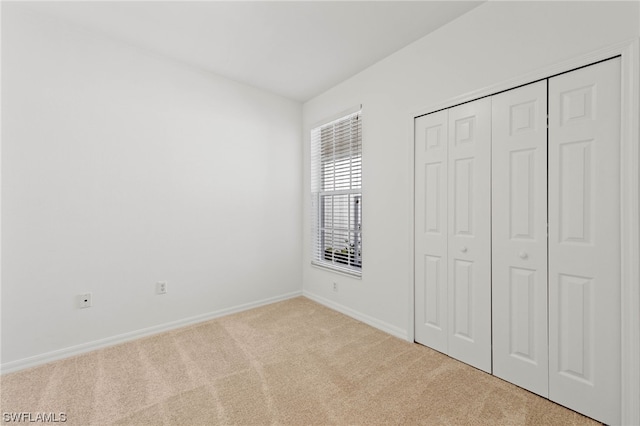 unfurnished bedroom featuring light carpet and a closet