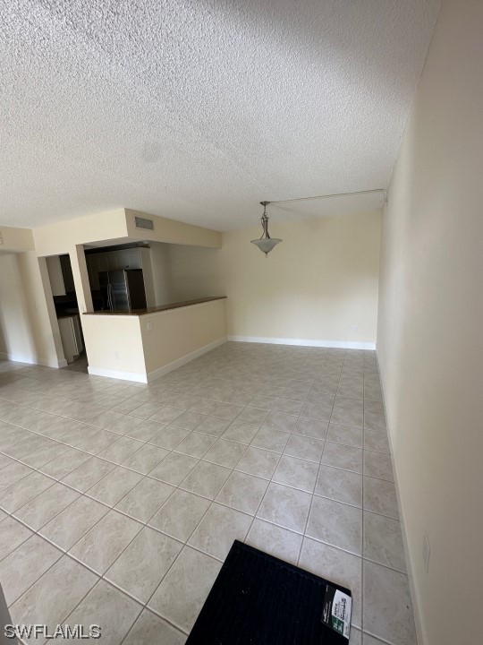 spare room featuring light tile floors and a textured ceiling