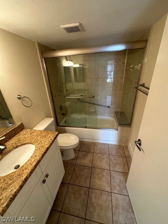 full bathroom with toilet, a textured ceiling, vanity, combined bath / shower with glass door, and tile flooring