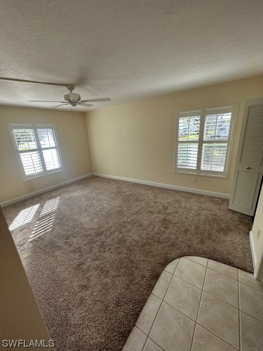 tiled empty room featuring ceiling fan and a textured ceiling