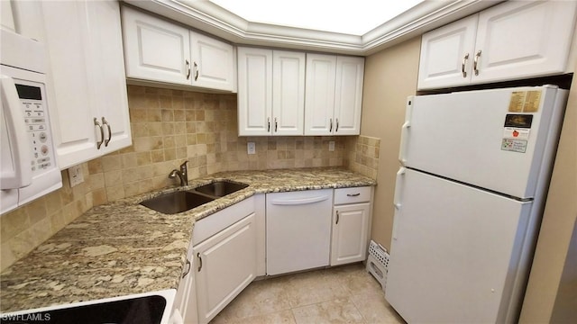 kitchen with tasteful backsplash, sink, white appliances, white cabinetry, and light stone countertops