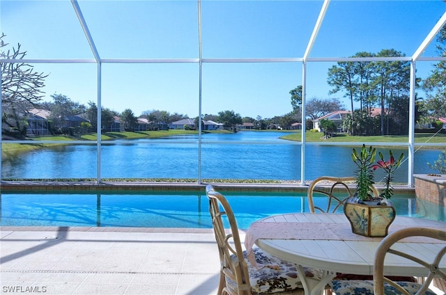 view of swimming pool featuring glass enclosure and a water view