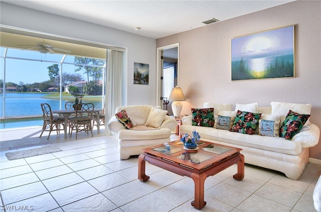 tiled living room featuring ceiling fan and a water view