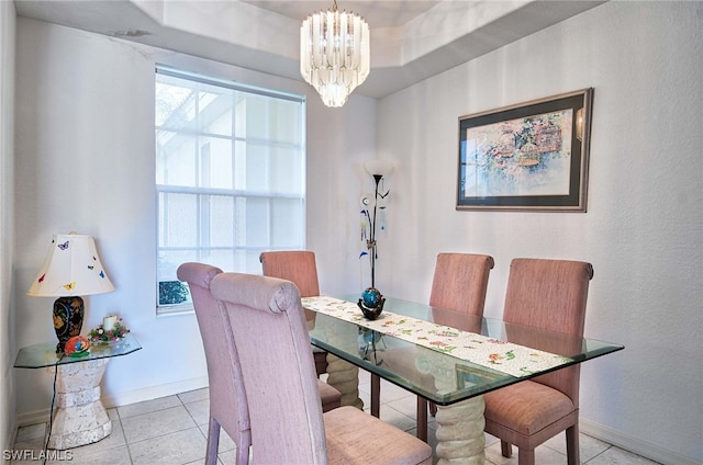 tiled dining area featuring a chandelier and a raised ceiling