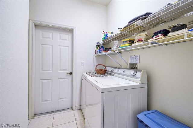 clothes washing area with light tile flooring, hookup for a washing machine, and washer and clothes dryer