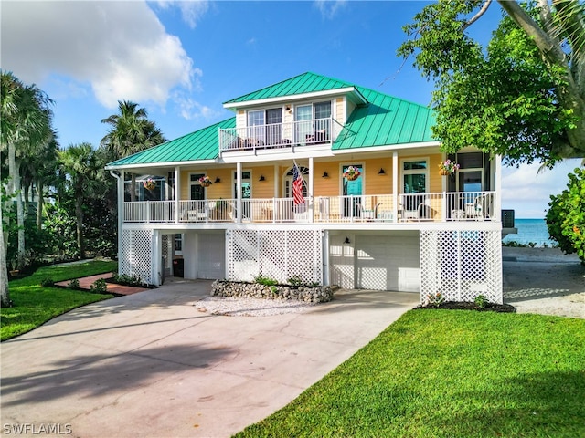 beach home featuring a garage, a porch, and a front yard