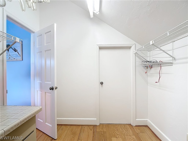 spacious closet with light hardwood / wood-style flooring and vaulted ceiling