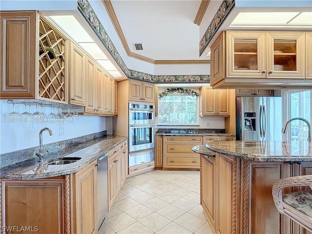 kitchen featuring light tile patterned flooring, a breakfast bar area, crown molding, dark stone counters, and appliances with stainless steel finishes