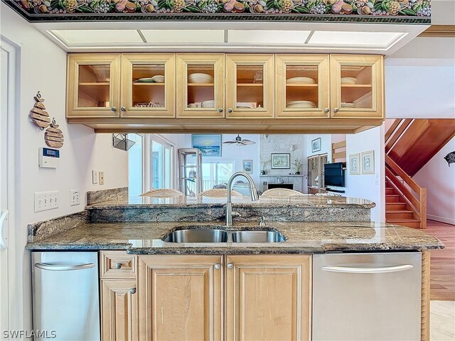 kitchen with stone counters, sink, light hardwood / wood-style floors, stainless steel dishwasher, and light brown cabinetry