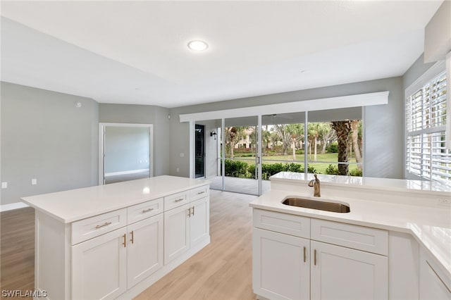 kitchen with light wood-type flooring, an island with sink, white cabinetry, and sink