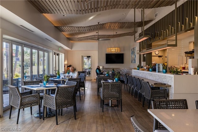 dining space with hardwood / wood-style floors and a towering ceiling