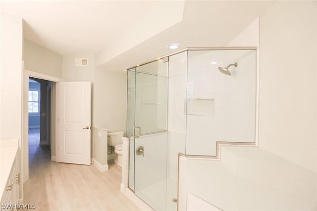 bathroom featuring toilet, vanity, an enclosed shower, and hardwood / wood-style flooring