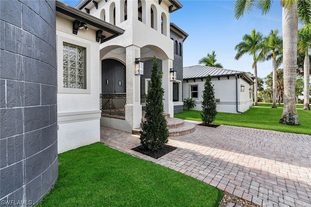 view of exterior entry featuring a lawn