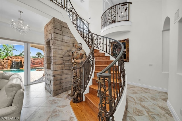 stairway with light tile flooring, a towering ceiling, and an inviting chandelier