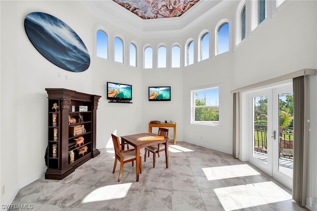 dining space with light tile flooring, plenty of natural light, a high ceiling, and french doors