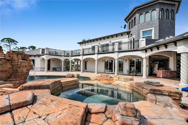 view of pool featuring an in ground hot tub, pool water feature, and a patio