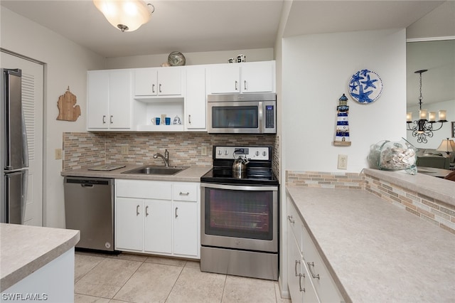 kitchen with sink, appliances with stainless steel finishes, backsplash, an inviting chandelier, and white cabinetry