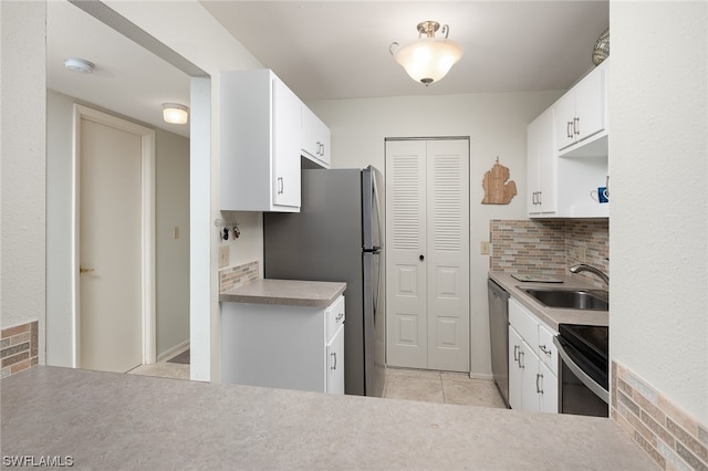 kitchen featuring sink, light tile floors, white cabinets, appliances with stainless steel finishes, and backsplash