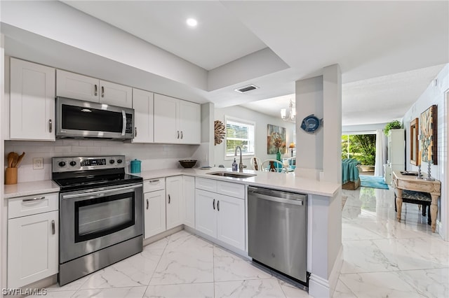 kitchen featuring kitchen peninsula, sink, white cabinets, and appliances with stainless steel finishes