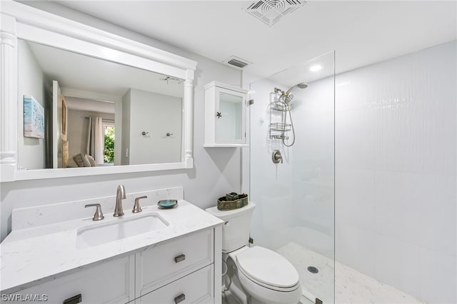 bathroom featuring a tile shower, vanity, and toilet