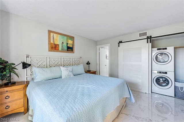 bedroom with stacked washer / dryer and a barn door