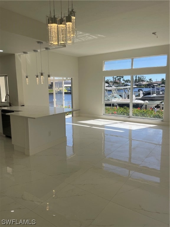 tiled empty room featuring a healthy amount of sunlight, a notable chandelier, and a water view