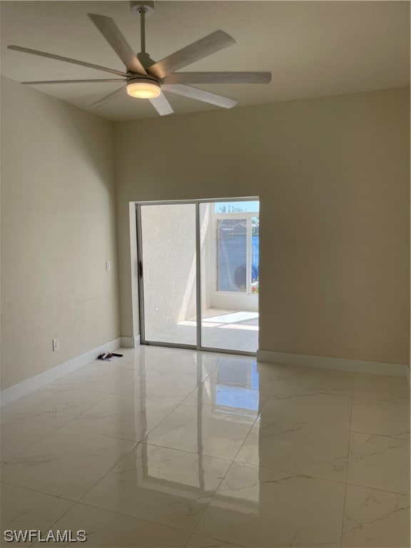 spare room with ceiling fan and light tile flooring