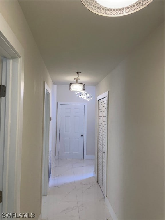 corridor with a notable chandelier and light tile floors