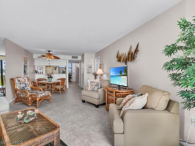 living room featuring ceiling fan, a textured ceiling, and light tile patterned floors