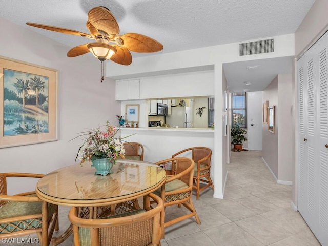 tiled dining area with ceiling fan and a textured ceiling