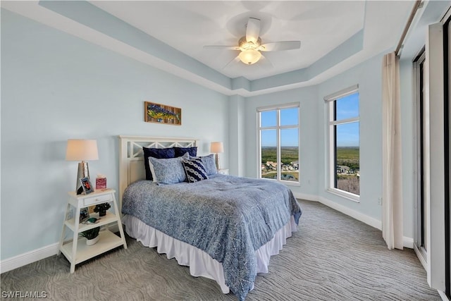 bedroom with carpet floors, a raised ceiling, and ceiling fan