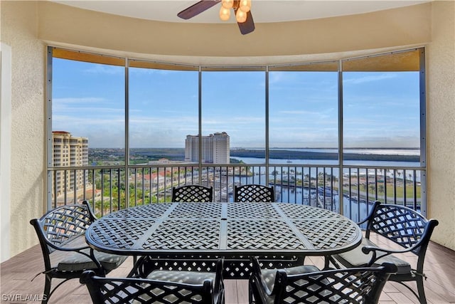 sunroom / solarium featuring a water view and ceiling fan