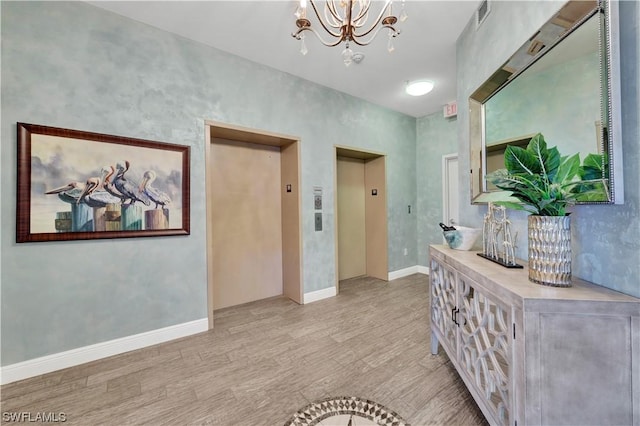 hall featuring a chandelier, elevator, and light hardwood / wood-style flooring