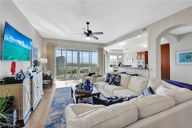 living room featuring ceiling fan, a fireplace, and light hardwood / wood-style flooring