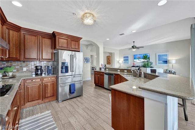 kitchen with sink, light hardwood / wood-style flooring, backsplash, a breakfast bar, and appliances with stainless steel finishes