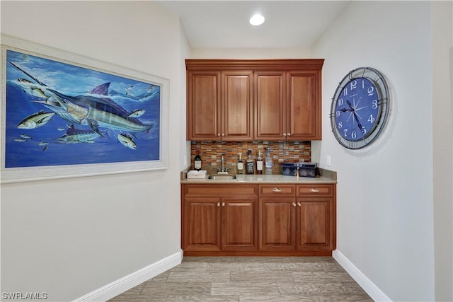 bar featuring decorative backsplash, light wood-type flooring, and sink