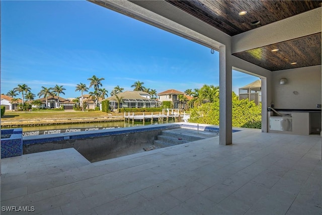 view of pool with a patio, a water view, and exterior kitchen