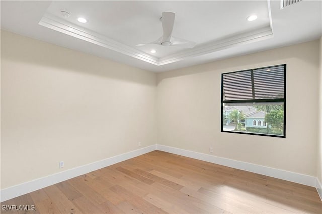 unfurnished room with ceiling fan, a raised ceiling, light wood-style flooring, and baseboards