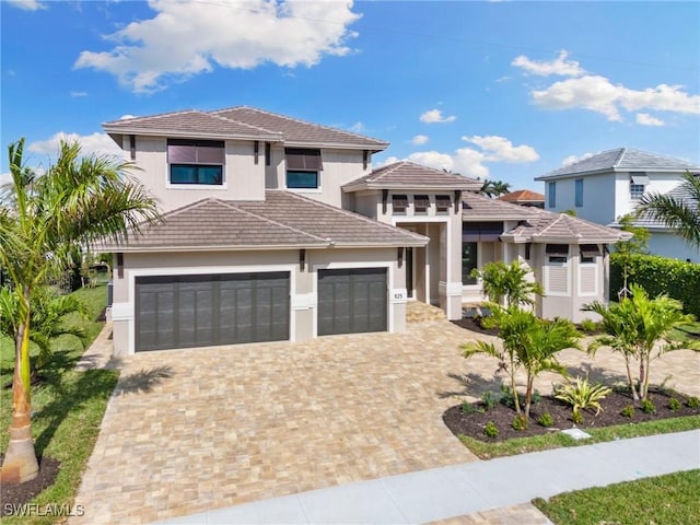 prairie-style house with a tiled roof, decorative driveway, an attached garage, and stucco siding