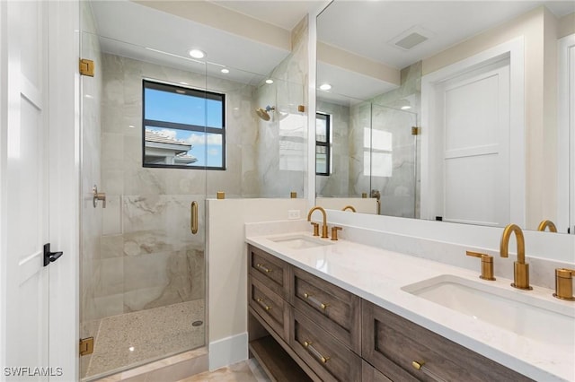 bathroom with double vanity, a shower stall, visible vents, and a sink