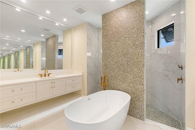 bathroom featuring visible vents, a soaking tub, vanity, tile walls, and recessed lighting