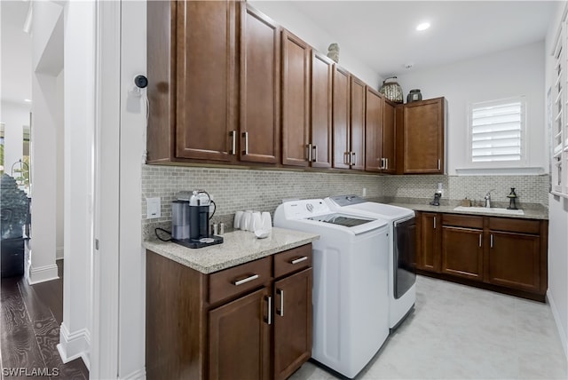 clothes washing area featuring cabinets, sink, light tile flooring, and washer and dryer