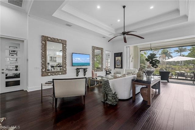 living room with a raised ceiling, ceiling fan, dark hardwood / wood-style flooring, and built in shelves