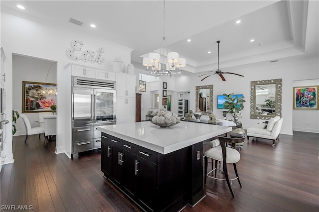 kitchen with a kitchen island, hanging light fixtures, ceiling fan with notable chandelier, and a tray ceiling