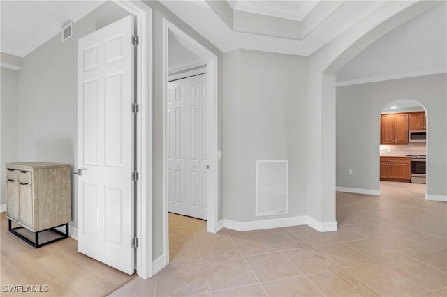 corridor with ornamental molding and light tile patterned floors