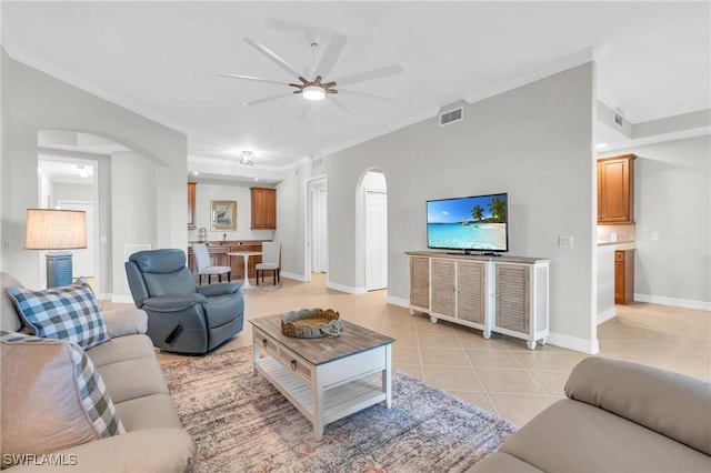 tiled living room with ceiling fan and crown molding