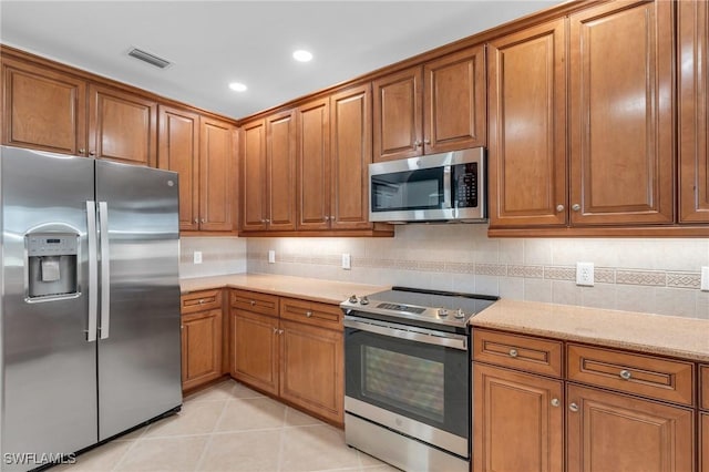 kitchen featuring backsplash, light tile patterned floors, and stainless steel appliances