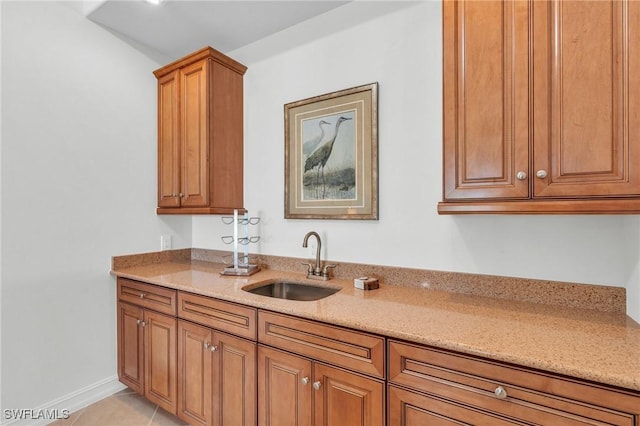 kitchen featuring light stone countertops, light tile patterned floors, and sink